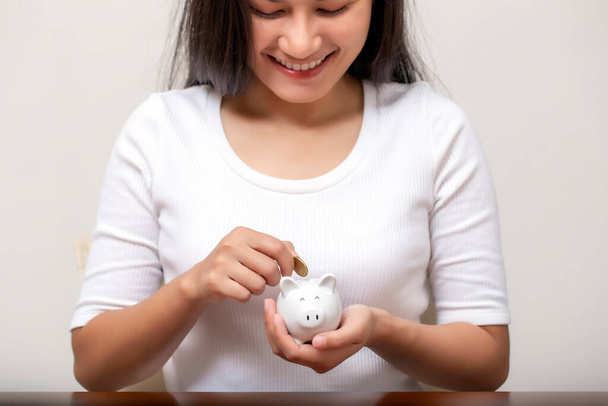 Boldog női kéz pénzt ad a malacperselynek, hogy pénzt takarítson meg.,  - Fotó, kép