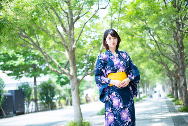 Aziatische (Japanse) vrouw gaat naar de stad in een yukata (Japans traditioneel kostuum)) - Foto, afbeelding