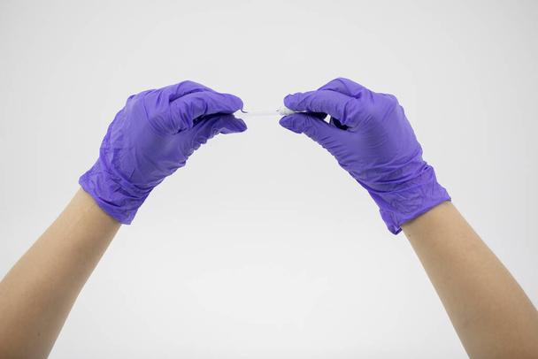 Kleine glazen buis met transparante vloeistof in handen van artsen met rubberen handschoenen - Foto, afbeelding