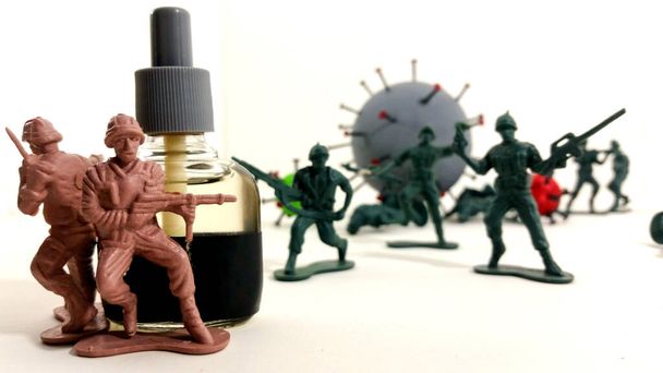 Toy soldiers fleeing the giant coronavirus while their companions protect themselves in a gel bottle. - Photo, Image