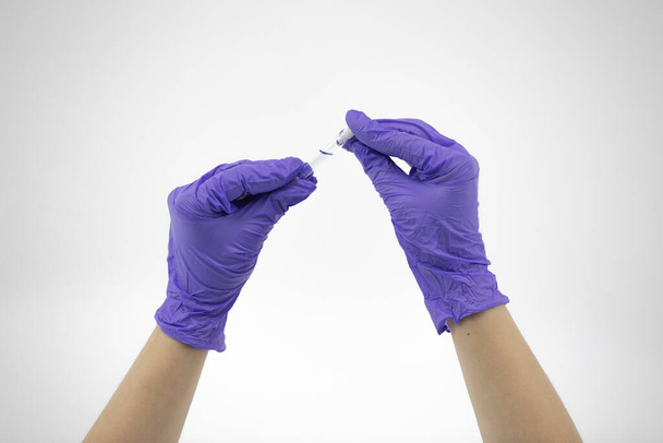 Mała szklana rurka z przezroczystym płynem w rękach lekarzy z gumowymi rękawiczkami - Zdjęcie, obraz