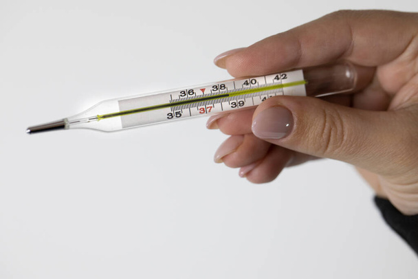 Закрыть медицинский термометр в женской руке, который показывает высокую температуру тела
 - Фото, изображение
