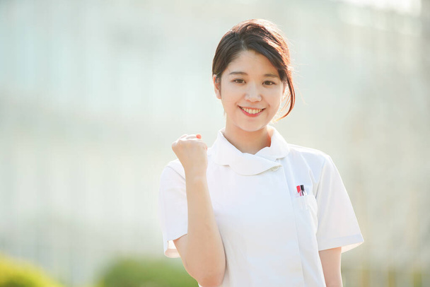 Asiática (japonesa) enfermera haciendo una pose tripas y animando con una sonrisa
 - Foto, imagen