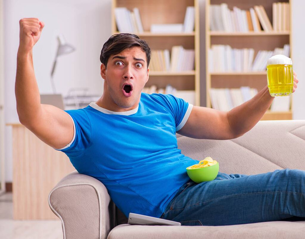Man watching football at home sitting in couch - Фото, изображение