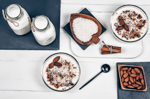 Homemade vanilla pudding with almonds, almond milk, coconut flakes and cinnamon on a white background - Foto, Bild
