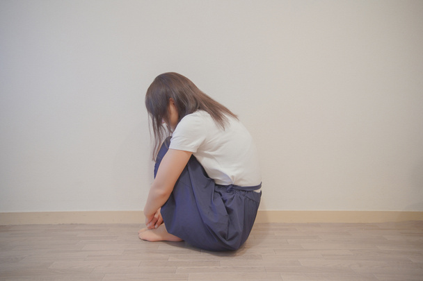 Ázsiai fiatal nő depressziós és leeresztett, hogy elrejtse arcát a hajával - Fotó, kép