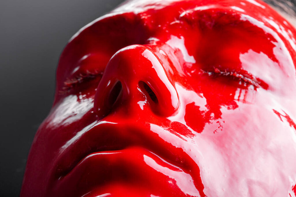 Image of a young females face with glossy red paint - Photo, Image