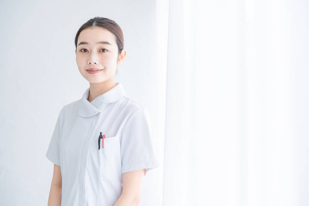 室内で笑顔を見せるアジア人女性看護師の肖像 - 写真・画像