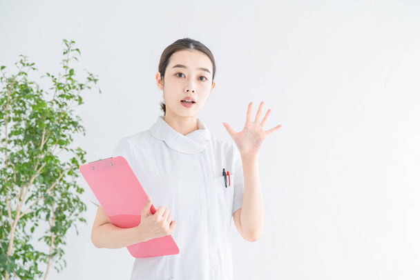 アジア系（日本人）女性看護師が手や表情で否定や拒絶を表現する - 写真・画像