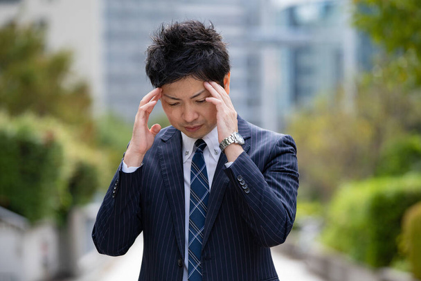 Persona de negocios asiática que sufre de dolor de cabeza debido al estrés en los negocios
 - Foto, Imagen