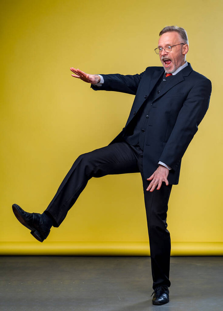 Senior manager man dancing at funny pose with expression. Yellow background. - Foto, Imagem