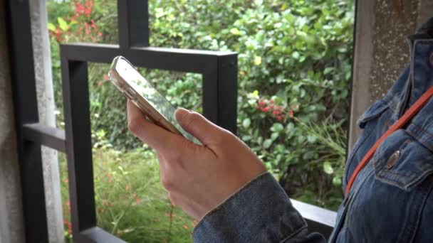 4K donna asiatica utilizzare il telefono cellulare sulla strada con sfondo della finestra tradizionale griglia reticolo cinese nel giardino di Taiwan. Utilizzando smartphone per navigare in internet-Dan
 - Filmati, video