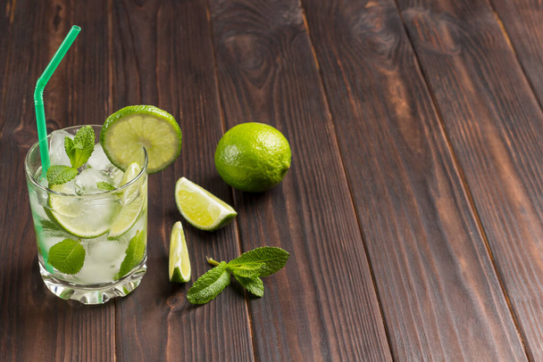 Summer cooling drink with ice, lime and mint. Non-alcoholic beverage. Dark wooden background. Copy space - Φωτογραφία, εικόνα