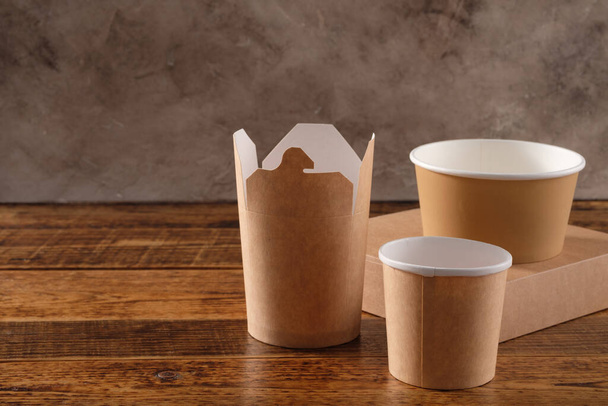 Street fast food paper cups, plates and containers. Eco-friendly food packaging on wooden background. Copy space. Carering of nature and recycling concept. - Photo, Image