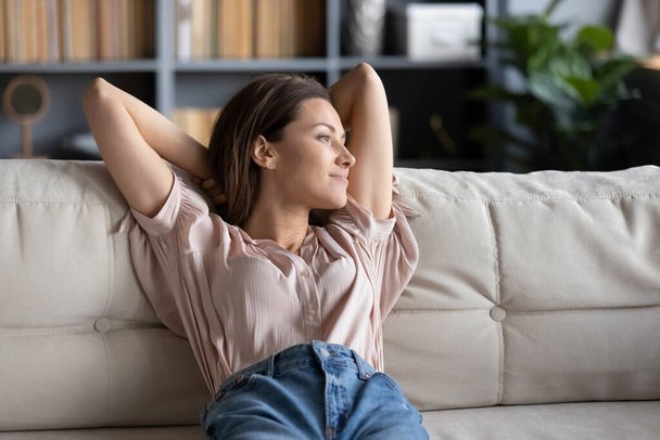 Peaceful young woman relaxing on couch at home - Foto, Bild