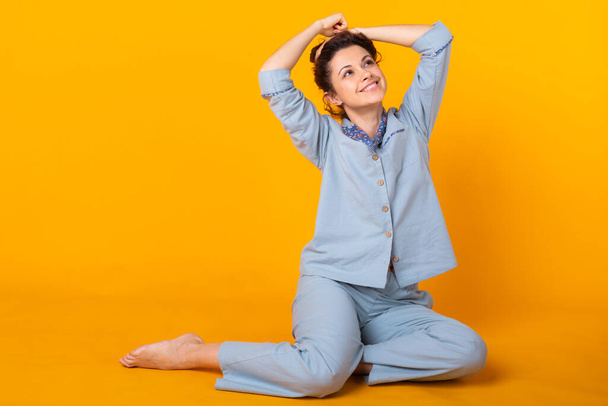 Young girl posing in pajamas on yellow background. Relax good mood, lifestyle and sleepwear concept. - Фото, изображение