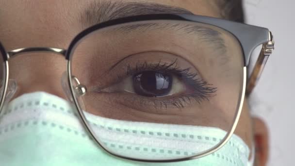 Macro close up of woman surgeon eye, doctor with protective face mask and glasses ready for operation. Essential healthcare professional at hospital. African American female in the disposable mask. - Filmati, video