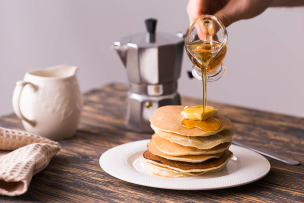 Male hand pouring maple syrup on tasty pancakes. - Zdjęcie, obraz