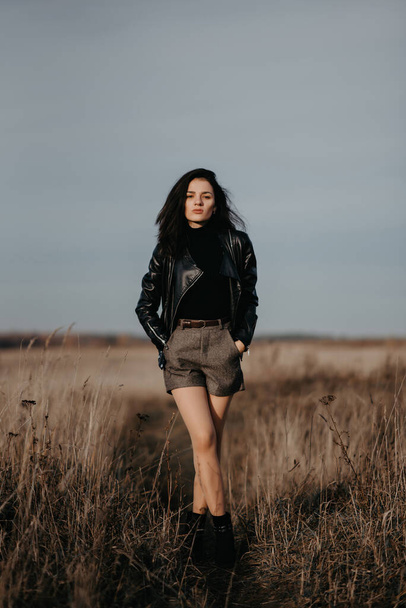 fashion girl in a leather jacket and shorts poses stylishly - Foto, Imagem