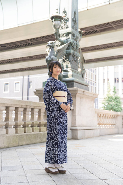 Ασιάτισσα (ιαπωνική) γυναίκα που πηγαίνει στην πόλη φορώντας ένα γιουκάτα (ιαπωνικό παραδοσιακό κοστούμι) - Φωτογραφία, εικόνα