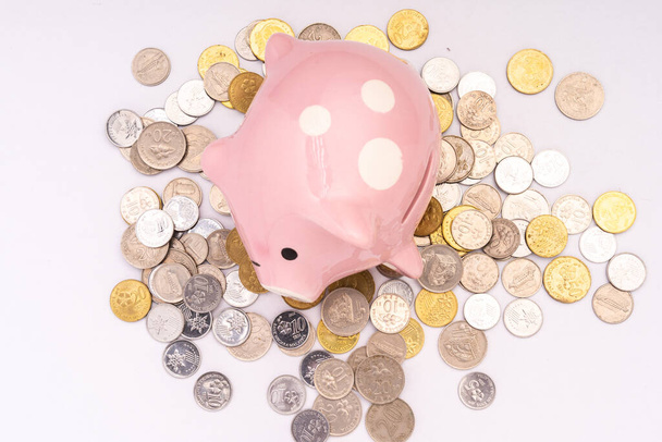 Piggy τράπεζα με διάσπαρτα κέρματα σε λευκό φόντο - Φωτογραφία, εικόνα
