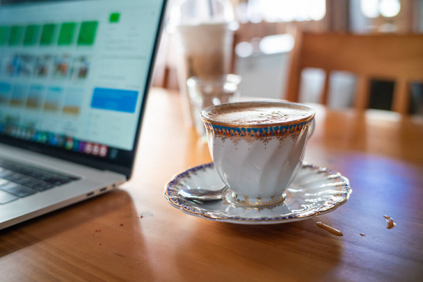 Hot aroma cappuccino csésze fa asztali munka otthonról laptop, Home business WFH koncepció - Fotó, kép