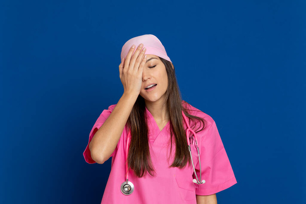 Młody lekarz w różowym mundurze na niebieskim tle - Zdjęcie, obraz