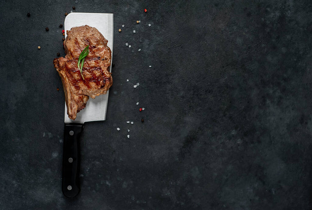 chinese cleaver knife and grilled ribs meat on a dark background - Photo, Image
