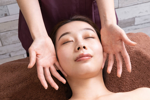 Une praticienne massant le visage d'une patiente asiatique
 - Photo, image