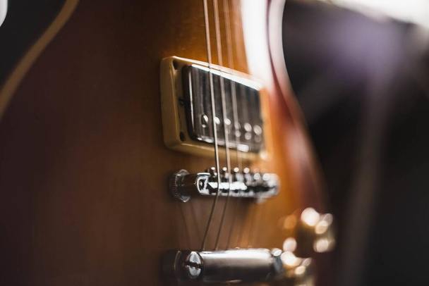 A closeup shot of the details of a brown guitar with a dark background - Foto, Imagen