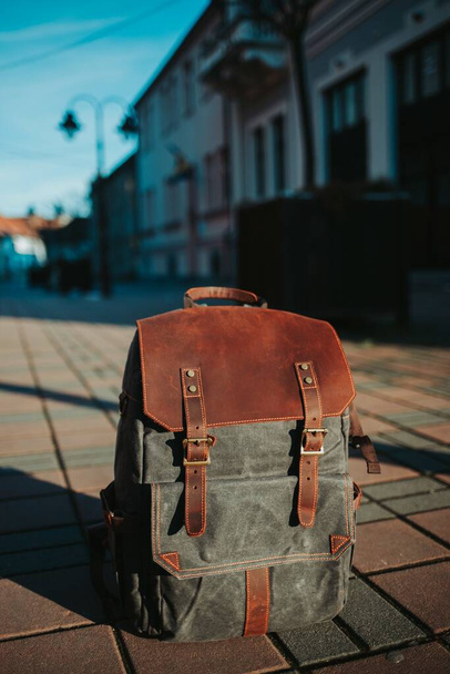 A vertical closeup shot of a grey and brown rucksack on the ground in the street - Foto, immagini