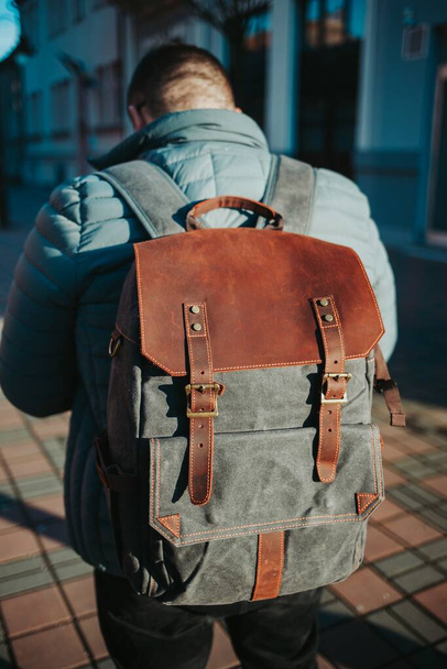 A vertical shallow focus shot of a male wearing a grey and brown rucksack - Valokuva, kuva