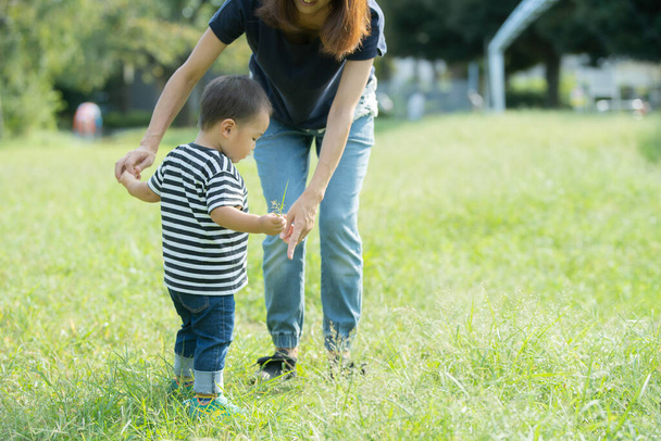 Two year old boy and his mother playing in the park on a sunny day - Foto, Imagen