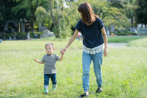 2歳の男の子と彼の母親は晴れた日に公園で遊んでいます - 写真・画像
