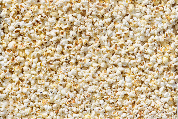 Large group of fresh cooked popcorn displayed for sale at a street food market, photographed with soft focus in warm yellow light, top view photo of healthy food photographed with soft focus - Фото, изображение