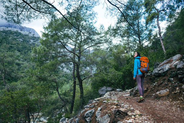 Une femme voyage seule dans des endroits pittoresques. Une fille avec un sac à dos longe un sentier de montagne. Une femme marche seule dans les bois. - Photo, image