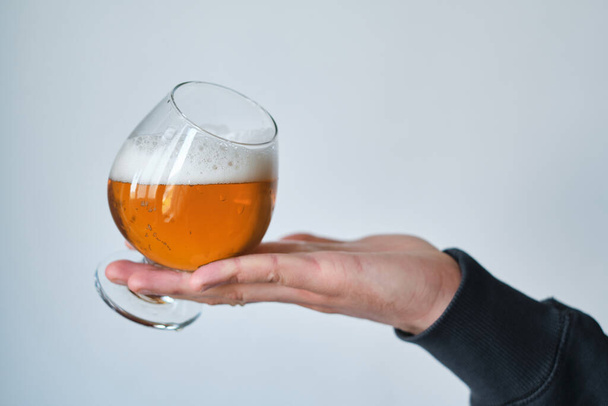 A glass of beer in the hands of a man. Tasting brewed craft beer. Lager beer with beautiful foam. Cold refreshment beverage. Alcohol drink from pub. Relaxation and enjoyment on beer degustation  - Foto, Imagem