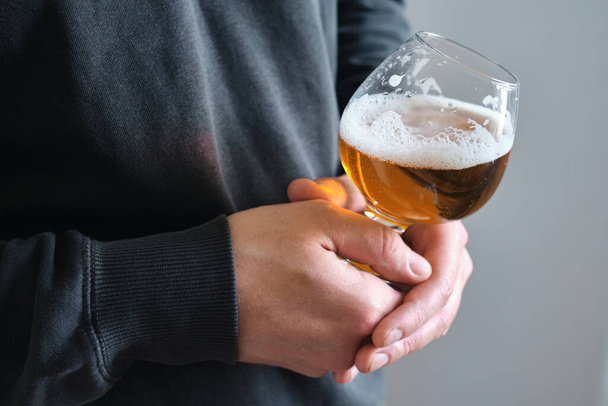 A glass of beer in the hands of a man. Tasting brewed craft beer. Lager beer with beautiful foam. Cold refreshment beverage. Alcohol drink from pub. Relaxation and enjoyment on beer degustation  - Фото, изображение