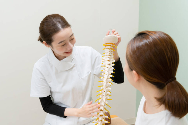 Asiatische Ärztin hört sich Symptom einer Patientin an und erklärt Behandlungsmethode - Foto, Bild