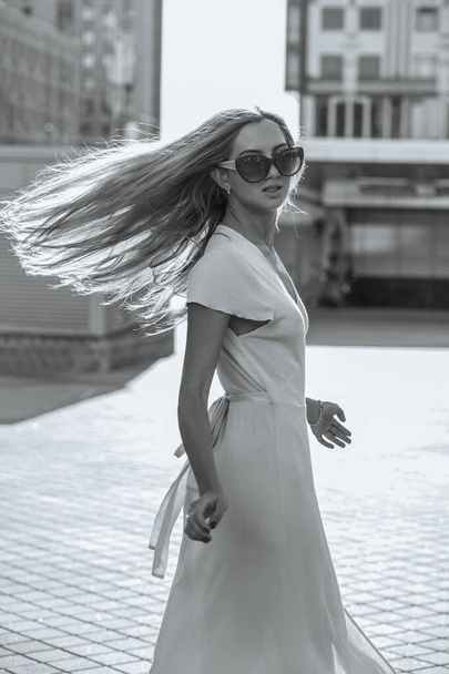 Fashionable blonde woman with long fluttering hair enjoying warm summer evening - Foto, Imagem