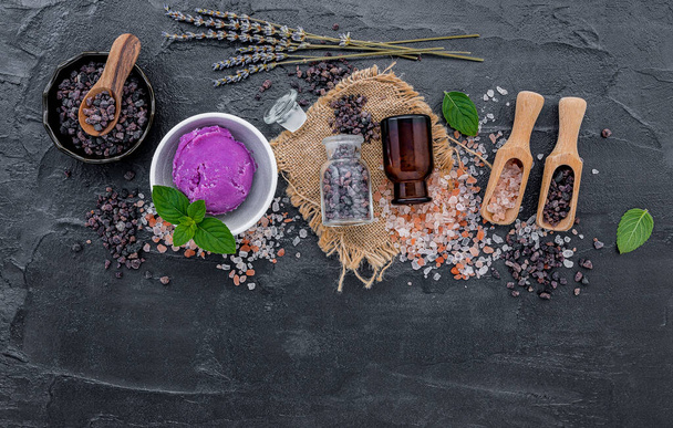 Гималайская черная соль и гималайская розовая соль с мятой и цветком лаванды на темно-бетонном фоне. Гималайская соль обычно используется для приготовления пищи и для продуктов для ванн, таких как соли для ванн
. - Фото, изображение