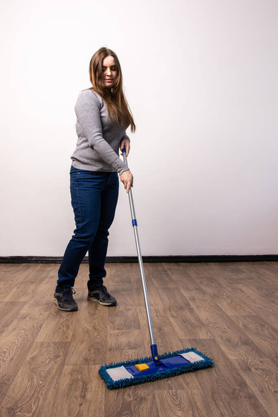 uma jovem de jeans esfrega o chão em um apartamento. limpeza de molas
. - Foto, Imagem