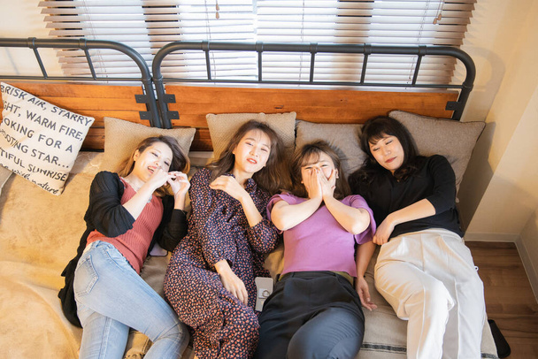 Cuatro mujeres jóvenes asiáticas tienen una conversación divertida en el dormitorio
 - Foto, Imagen