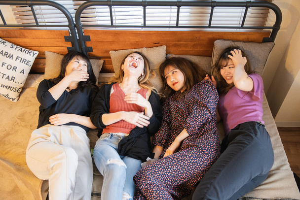 Cuatro mujeres jóvenes asiáticas tienen una conversación divertida en el dormitorio
 - Foto, imagen