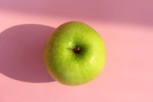 Green apple on a pink background. Juicy ripe beautiful fruit - Foto, afbeelding