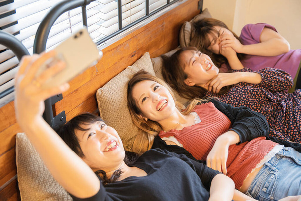 Cuatro mujeres jóvenes asiáticas tienen una diversión para tomar una foto del teléfono inteligente
 - Foto, Imagen