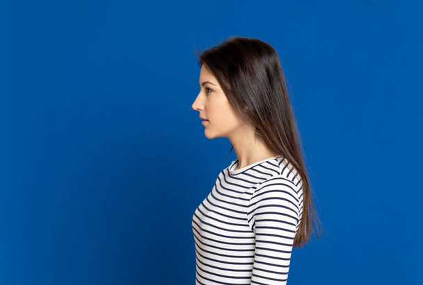 Brunette young woman wearing a striped T-shirt on a blue background - Foto, afbeelding