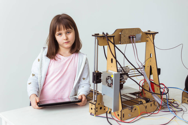 Linda chica con persianas impresas en 3D está viendo su impresora 3d, ya que imprime su modelo 3d
. - Foto, imagen