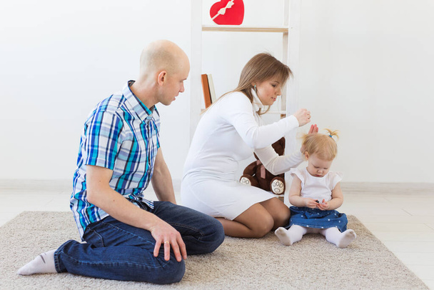 Happy family, mother, father and their baby together in living room at home. Children and toddler concept. - Photo, Image