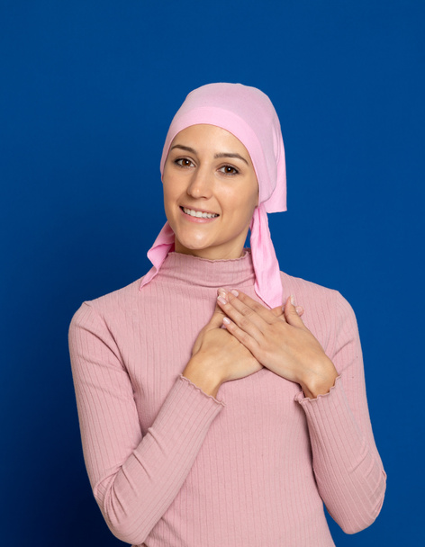 Mujer joven con bufanda rosa en la cabeza sobre un fondo azul
 - Foto, imagen